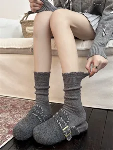 Detailaufnahme von kuscheligen grauen Wollsocken und Hausschuhen im gemütlichen Indoor-Look.