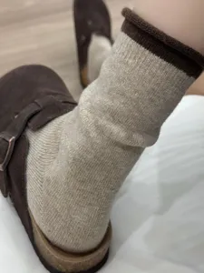 Calze al polpaccio in maglia beige con risvolto marrone, dettaglio caldo per l'inverno.