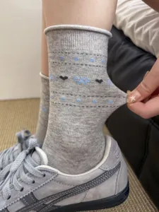 Close-up view of grey cotton mid-tube socks featuring cute heart and bow knit patterns detail.