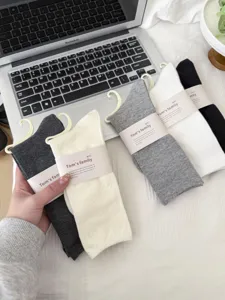 Detailed shot of comfortable cotton slouch socks in classic black, white, and grey colors.