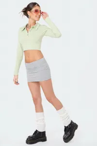 Completo elegante da donna con polo corta e mini gonna micro abbinato a stivali estivi.