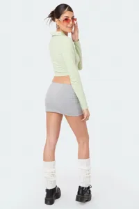 Vista dettagliata dell'outfit casual da donna con crop top tinta unita e minigonna grigia.