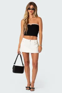 Gedetailleerd overzicht van chique zwarte bandeau-top gecombineerd met witte denimrok.