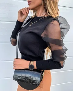 Details of women's black long sleeve top with elegant sheer mesh puff sleeves and knit body.