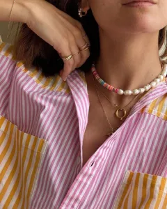 Close-up detail of a pink and yellow striped button-down shirt with a front chest pocket.