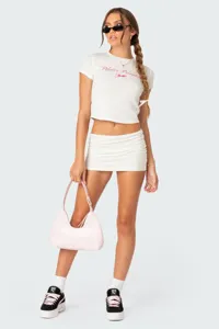 Vista di dettaglio del completo estivo casual crop top e minigonna con borsa rosa e sneakers.