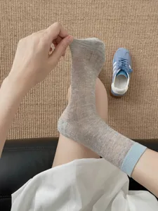 Sheer grey mid-calf socks detail, lightweight breathable mesh design with blue cuff.
