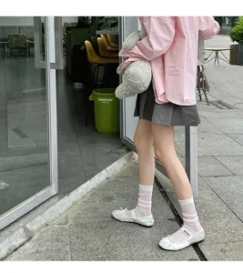 Detail view of grey striped mid-calf socks paired with white flat shoes in a street style scene.
