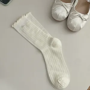 Detail shot of white ruffle trim crew socks with cute flower button, soft knit texture.