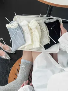 Close-up of ballet-style bow socks with pearl details, elegant display on a tray.
