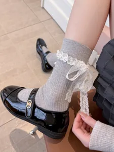 Detail shot of grey ribbed socks with white lace trim, bow ribbon, and black Mary Jane shoes.