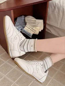 Detailopname van stijlvolle gestreepte sokken gecombineerd met retroschoenen in een gezellige kamer.