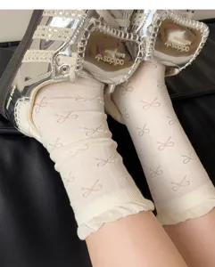 Detailed close-up of white sheer crew socks featuring delicate bow patterns and ruffled cuffs.