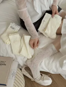 Cream white lace hollow floral mid-calf socks detail showing delicate knit and bow design.
