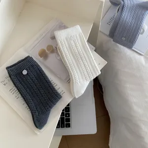 Detailed shot of Korean style solid twist knit socks with delicate shell button accent.