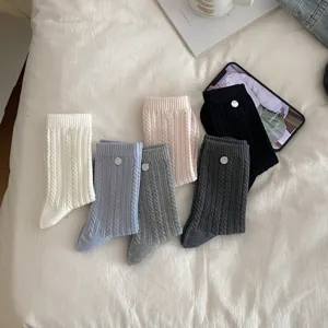 Korean style solid color mid-calf cable knit socks for women with cute shell button decor.