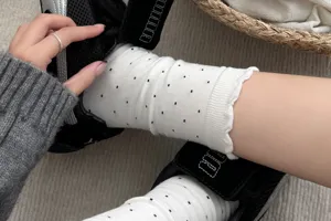 Nahaufnahme von weißen Damen Baumwollsocken mit schwarzen Punkten und Rüschenkante.