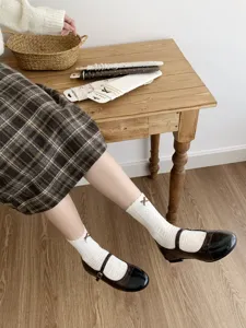 Close-up detail of cute white lace bow socks styled with sweet Mary Jane shoes in interior.