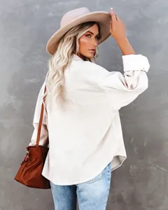 Detail view of casual women's corduroy button-down shirt jacket with long sleeves and lapel.