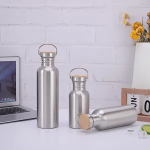 Detailed view of stainless steel water bottles with bamboo lids and handles on desk.