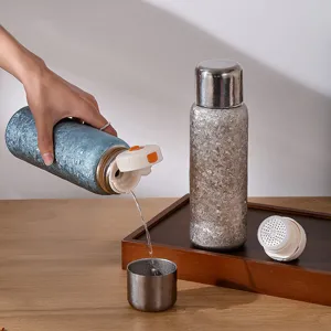 Détail de la bouteille isotherme en titane avec filtre à thé et tasse de bureau élégante.