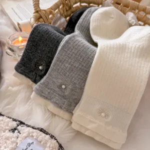 Close-up detail of cozy winter ribbed mid-tube socks with cute pearl bow and contrast cuff.