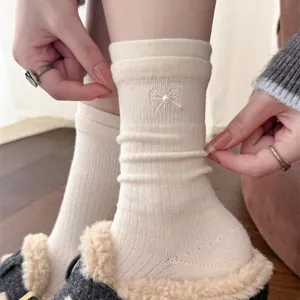 White knit crew socks with cute pearl bow embroidery, cozy winter hosiery detail shot.