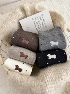 Close-up detail of cute dachshund embroidered knit socks with polka dot pattern in cozy basket.