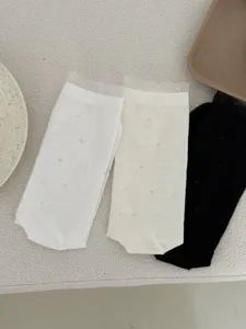 Close-up of sheer lace ruffle mid-tube socks in white, beige, and black with subtle heart patterns.