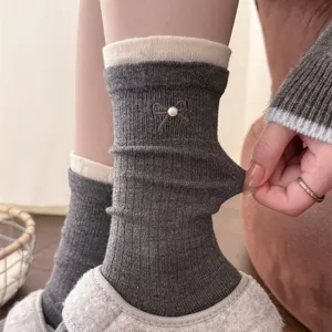Detail view of ribbed cashmere socks featuring a chic pearl bow and contrast cuff design.