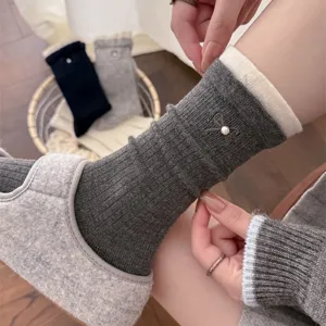 Detailed shot of Korean style women winter mid-tube socks in dark grey with pearl bow and white contrast cuff.