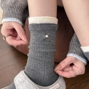 Close-up detail view of grey ribbed mid-calf socks featuring delicate pearl and bow embroidery.