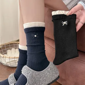 Detail view of women's autumn winter cashmere mid-calf socks with pearl bow and contrast color cuff.
