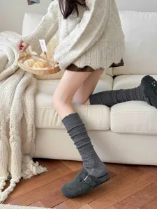 Detailed lifestyle shot of cozy grey knit slouch long socks worn on sofa, soft warm texture.
