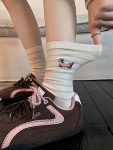 Close-up of cotton striped mid-calf socks featuring cute embroidered dachshund design.
