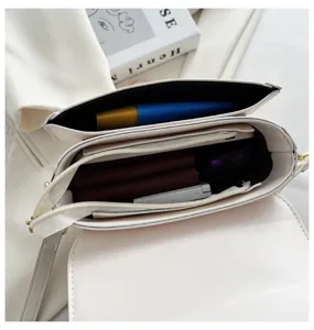 White minimalist women's saddle shoulder bag, detailed view of multi-compartment interior storage.