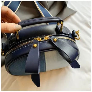 Nahaufnahme des stilvollen blauen Jeans- und Leder-Patchwork-Umhängetags mit goldener Hardware.