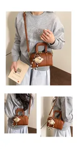 Detailansicht der Vintage Litschi-Textur Boston Handtasche mit Bärenanhänger und Gurt.