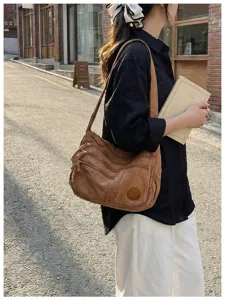 Detailansicht einer braunen Canvas Umhängetasche, getragen von einem Model auf der Straße.