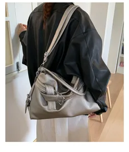 Detail view of a vintage metallic silver motorcycle shoulder bag with buckle and slouchy design.