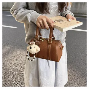Detailansicht der braunen strukturierten Retro-Kissenhandtasche mit süßem Plüsch-Bärenanhänger.