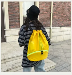 Detailaufnahme des gelben Kordelzug-Sportrucksacks mit vertikalen grünen Streifen und Taschen.