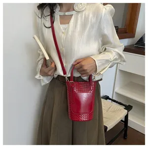 Red woven bucket bag detail view, stylish shoulder bag with top handle and strap.
