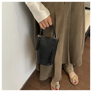 Detail view of a chic black woven bucket handbag, showcasing trendy design and premium texture.