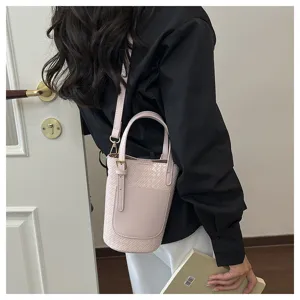 Detail view of stylish pink woven bucket bag for women, modern shoulder handbag.