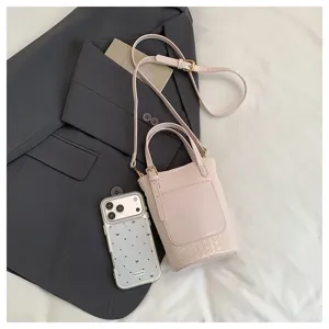 Detailed shot of stylish pink woven bucket bag paired with a grey blazer and phone accessory.
