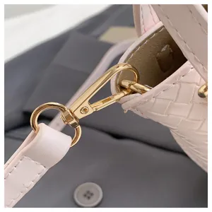 Detailed shot of pink woven leather women handbag shoulder strap gold hardware close up