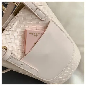 Pink woven leather handbag detail, stylish bucket bag shoulder strap closeup view.