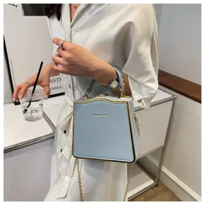 Light blue structured box bag with golden metal trim and chain strap for women detail view.