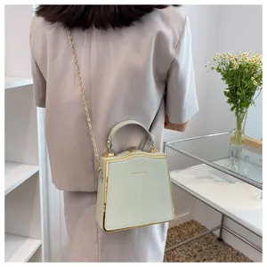 Detailed view of the mint green structured box bag featuring shiny gold chain and metal edge trim.